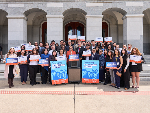 Lawmakers, education leaders, and students stand in front of the state capitol with signs that say "Empowering California's Future"