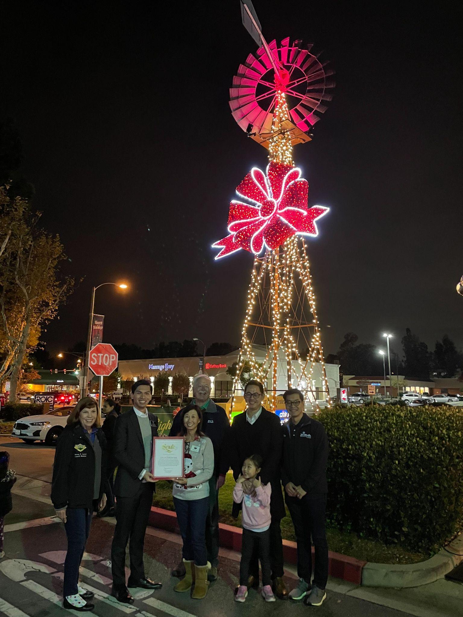 Group of people near lighted up Christmas windmill.